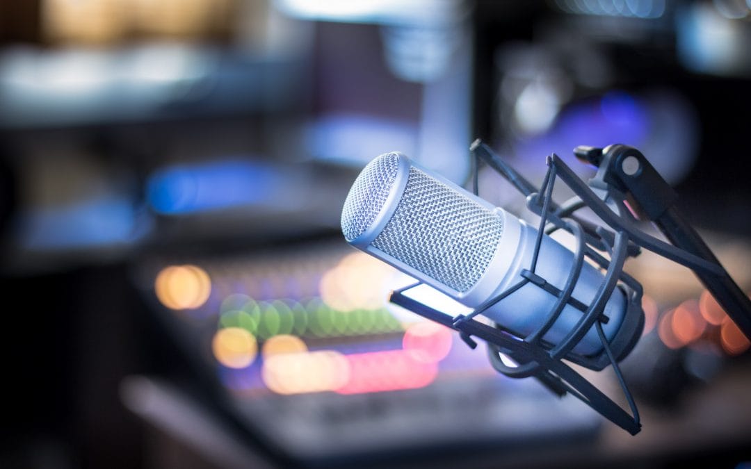 Microphone in a professional recording or radio studio, equipment in the blurry background